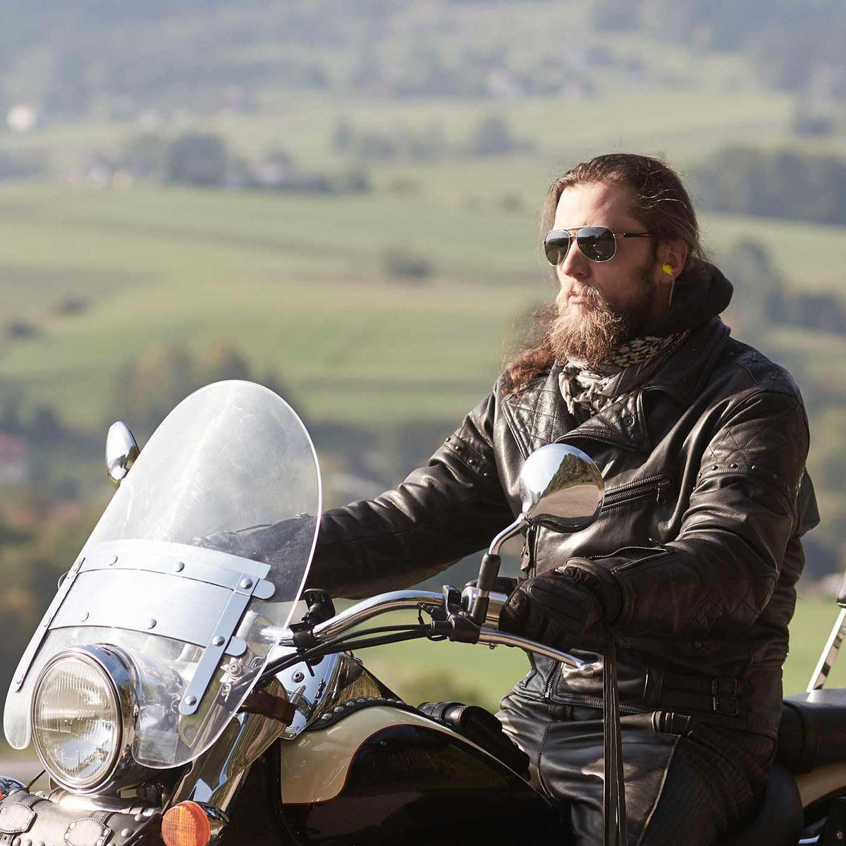 A man wearing the Elgin Ruckus Black Wired Earplug Earbuds while riding a motorcycle. Elgin® USA